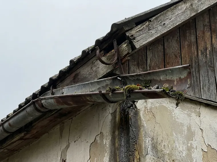 Durchgerostete Dachrinne mit Wasserspur an der Fassade